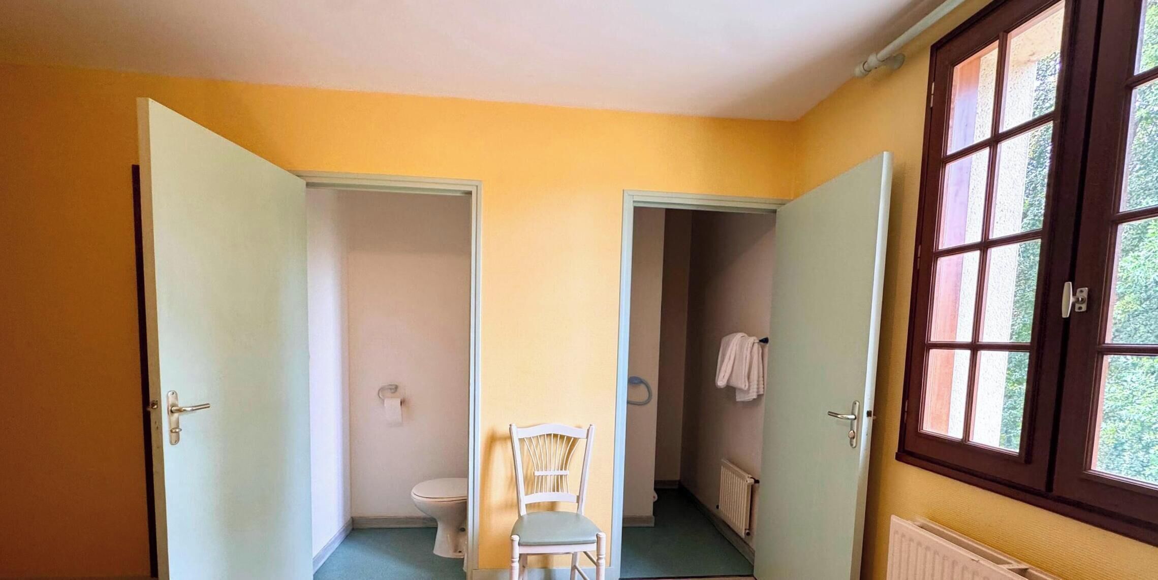 Une pièce dotée de deux portes, l’une donnant sur une salle de bain et l’autre sur un couloir.