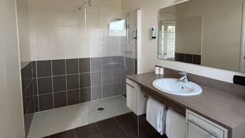 Une salle de bain moderne avec une douche, un lavabo et un miroir.