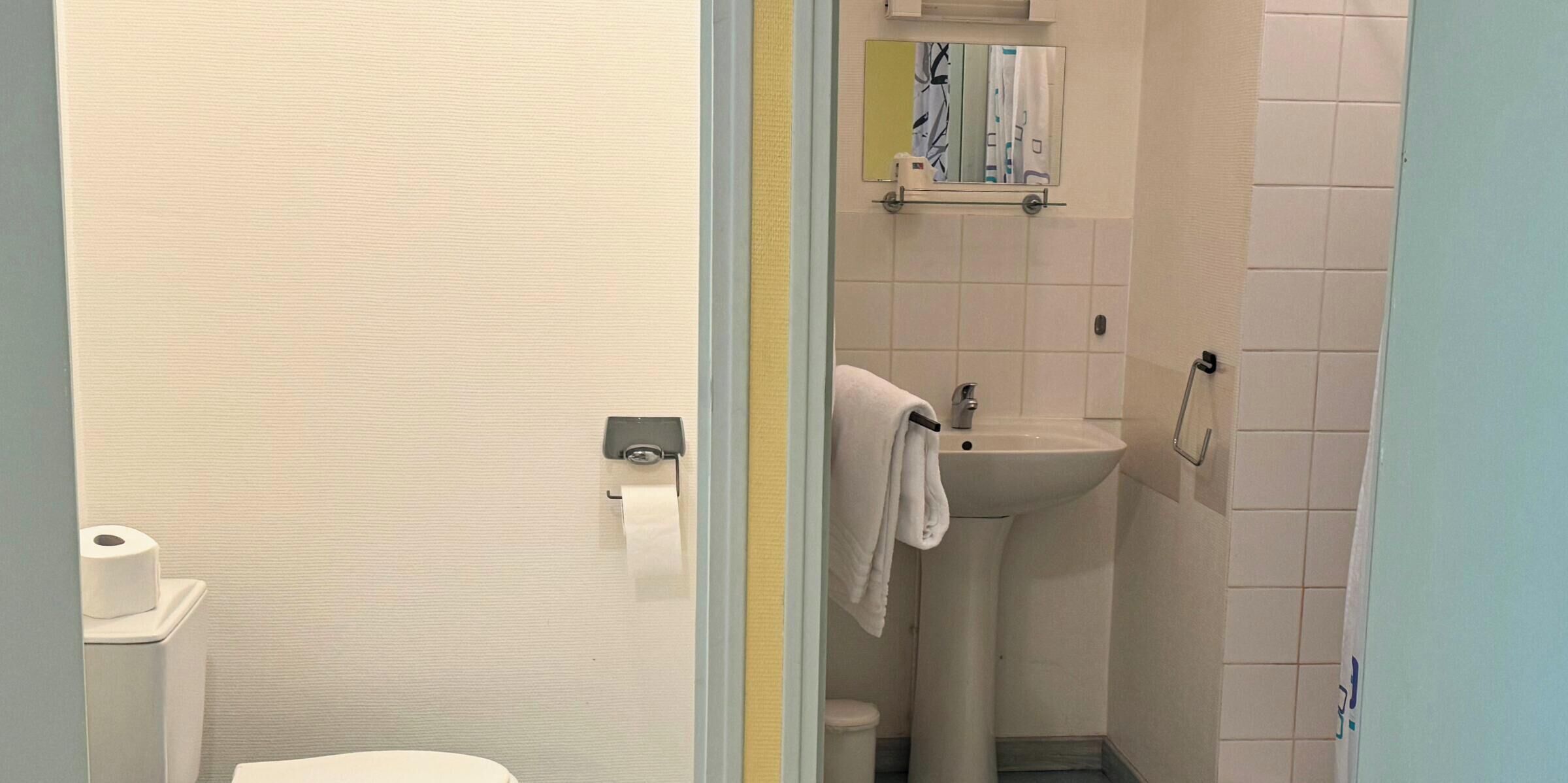 A small bathroom with a toilet, sink, and a towel hanging on the wall.