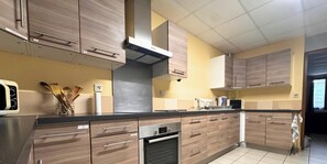 Eine Küche mit Holzschränken, einer Edelstahl-Dunstabzugshaube und einer gefliesten Spritzschutzwand.