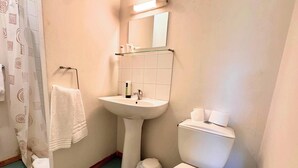 A bathroom with a white sink, a toilet, and a shower curtain with a geometric pattern. - Room 109 - Le Bas Mont Residence (Moulay)