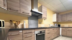 A kitchen with wooden cabinets, a stainless steel range hood, and a tiled backsplash. - Room 104 - Le Bas Mont Residence (Moulay)