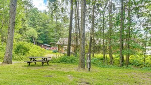 Ein Picknicktisch in einer bewaldeten Gegend, im Hintergrund eine Holzhütte.