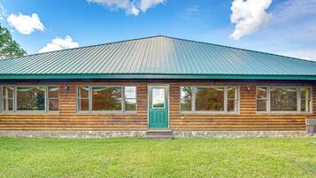 A wooden cabin with a green door, large windows, and a metal roof.