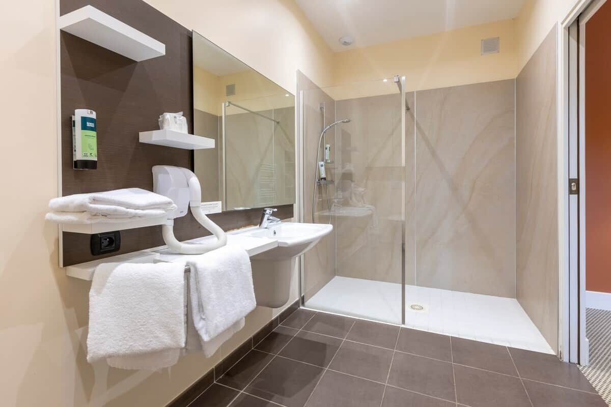 Une salle de bain moderne avec une douche à parois de verre, un lavabo blanc et un miroir au-dessus.