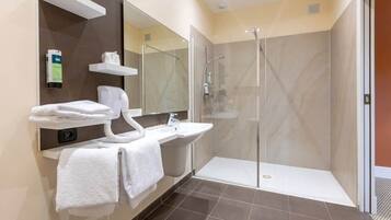 Une salle de bain moderne avec une douche à parois de verre, un lavabo blanc et un miroir au-dessus.