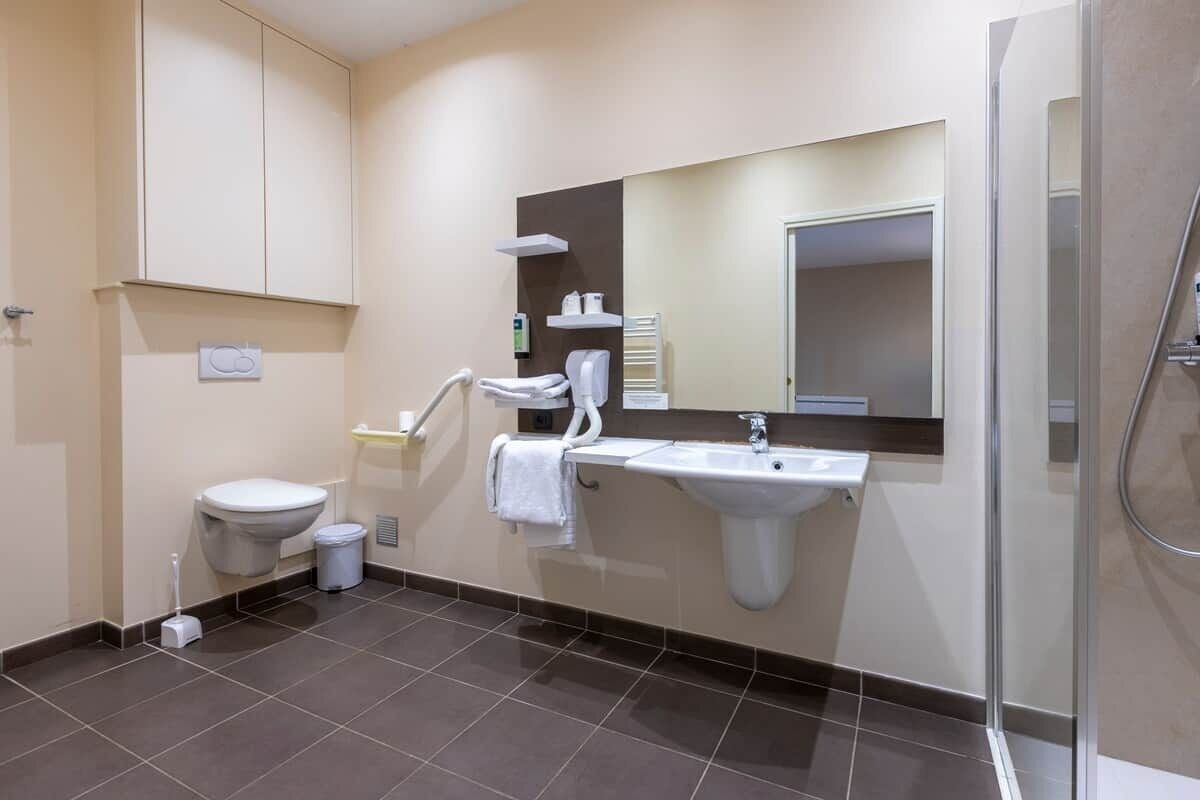 Een moderne badkamer met toilet, wastafel en douche.