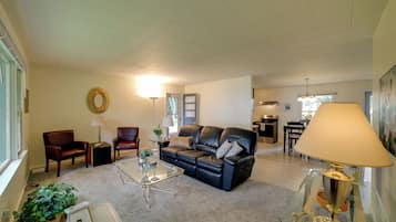 A living room with a sofa, chairs, a coffee table, and a lamp.