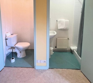 Une salle de bain comprenant des toilettes, un bidet et un espace douche.