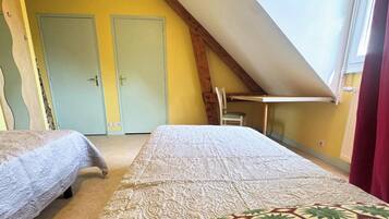 Een slaapkamer met twee bedden, een schuine kap en een raam.