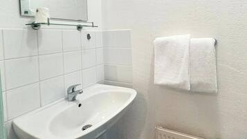 Un baño con un lavamanos blanco, un espejo, un toallero con dos toallas y un radiador.