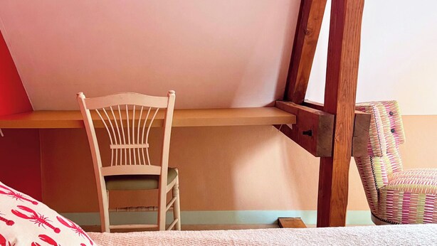 A room with a wooden chair, a bed with a red and white patterned pillow, and a wooden desk. - Room 202 - Le Bas Mont Residence (Moulay)