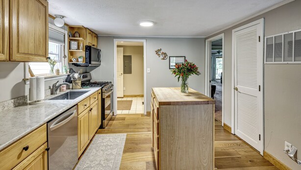 A kitchen with wooden cabinets, a stove, and a sink. - Game Room, Deck + Yard! Cadillac Family Escape (Cadillac)