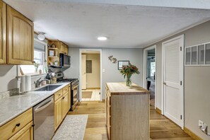A kitchen with wooden cabinets, a stove, and a sink. - Cadillac Escape w/ Game Room, Deck & Yard! (Cadillac)