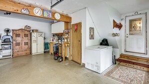 A garage with a wooden ceiling, a clock, a refrigerator, and a door with a decorative glass panel. - Game Room, Deck + Yard! Cadillac Family Escape (Cadillac)
