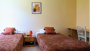 A room with two beds, each with a brown blanket and a pillow, a small table with a lamp, and a chair. - Room 105 - Le Bas Mont Residence (Moulay)