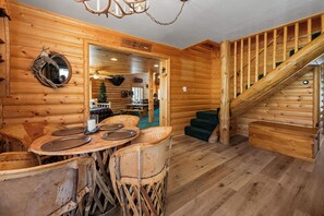 L’intérieur d’un chalet en bois, avec une table à manger, des chaises, un miroir et un escalier.