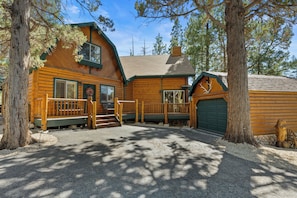 A log cabin with a porch, a garage, and a stone wall. - All Seasons Lodge: Family Haven in Big Bear (Big Bear Lake)