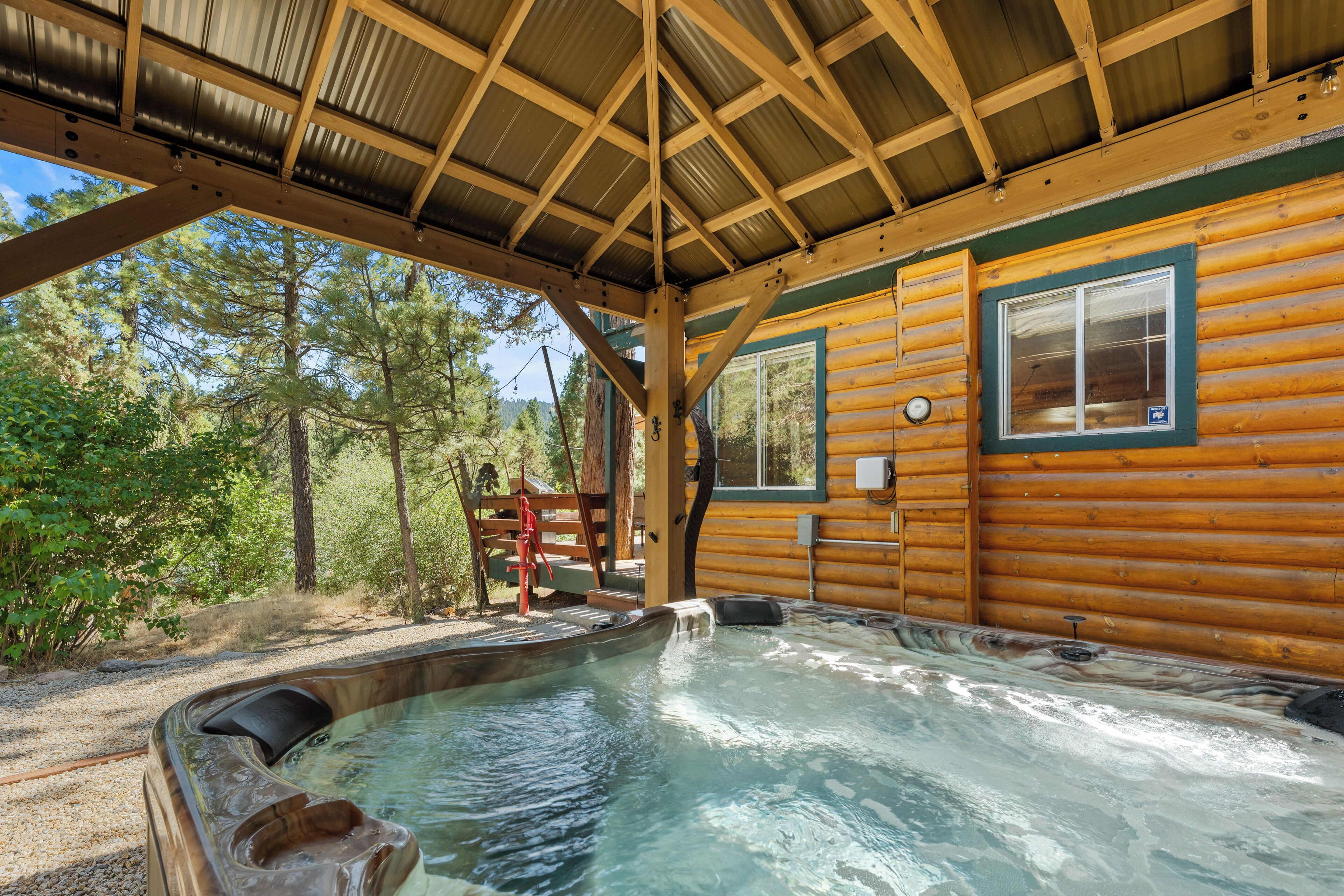 Une cabane en bois avec un jacuzzi, une fenêtre et une vue sur la forêt.
