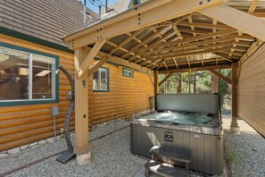 Une cabane en bois dotée d’un bain à remous et d’une terrasse couverte.