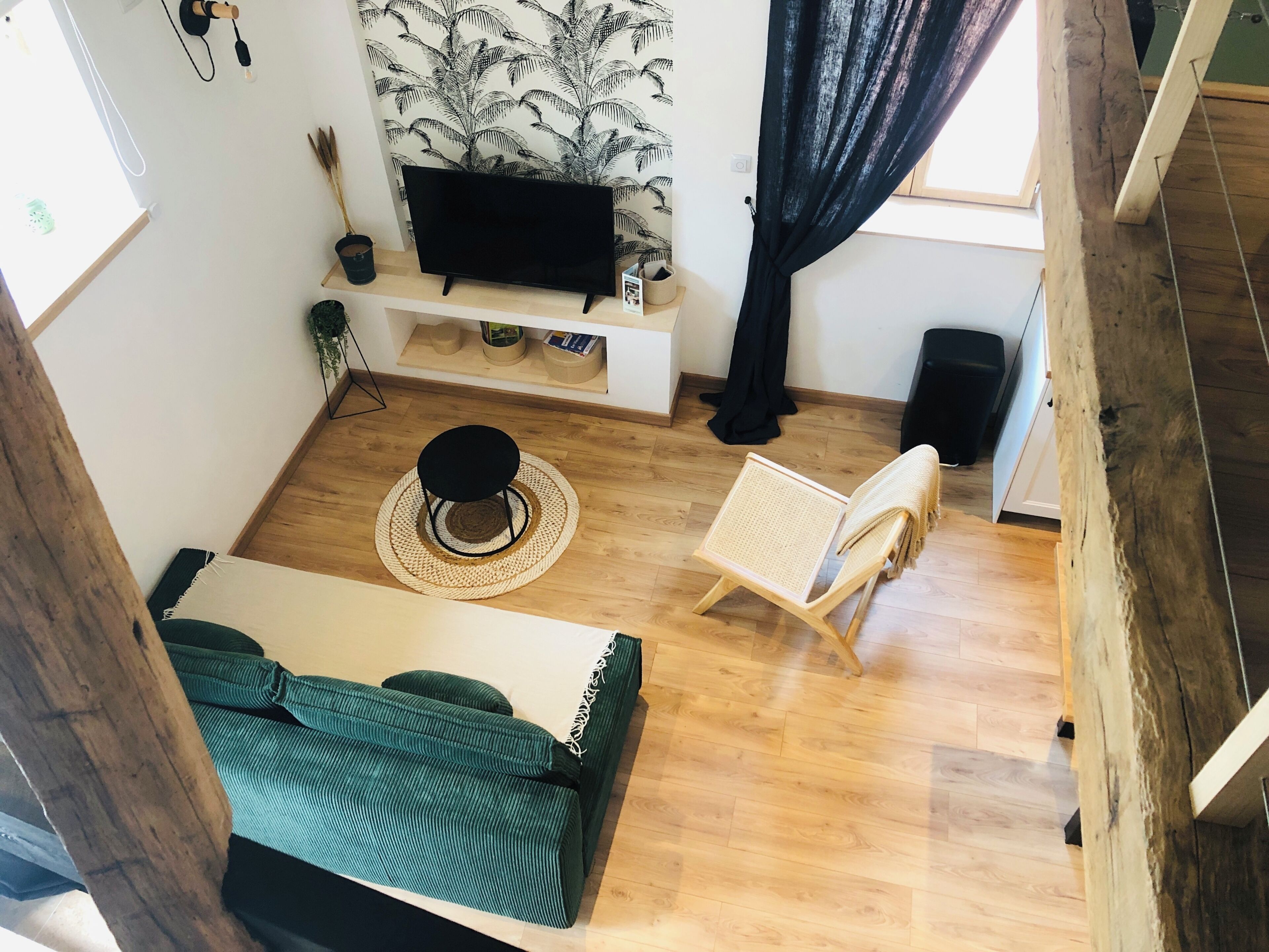 Una sala de estar moderna con un sofá, una mesita redonda, una silla, un televisor y una estantería.