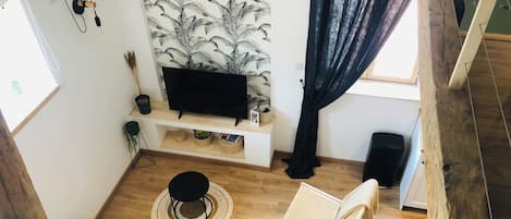 A modern living room with a sofa, a small round table, a chair, a television, and a bookshelf.