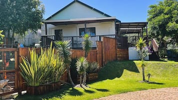 A residential property with a fenced yard, a covered patio, and a paved driveway.