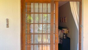 Une porte en bois avec des panneaux de verre, un sol carrelé et une petite table avec une lampe.