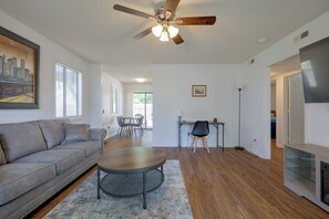 A living room with a ceiling fan, a sofa, a dining table with chairs, and a TV. - Walk to Med Center! Extended Wilmington Condo (Wilmington)