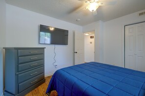 A bedroom with a bed, dresser, television, and a door leading to another room. - Walk to Med Center! Extended Wilmington Condo (Wilmington)