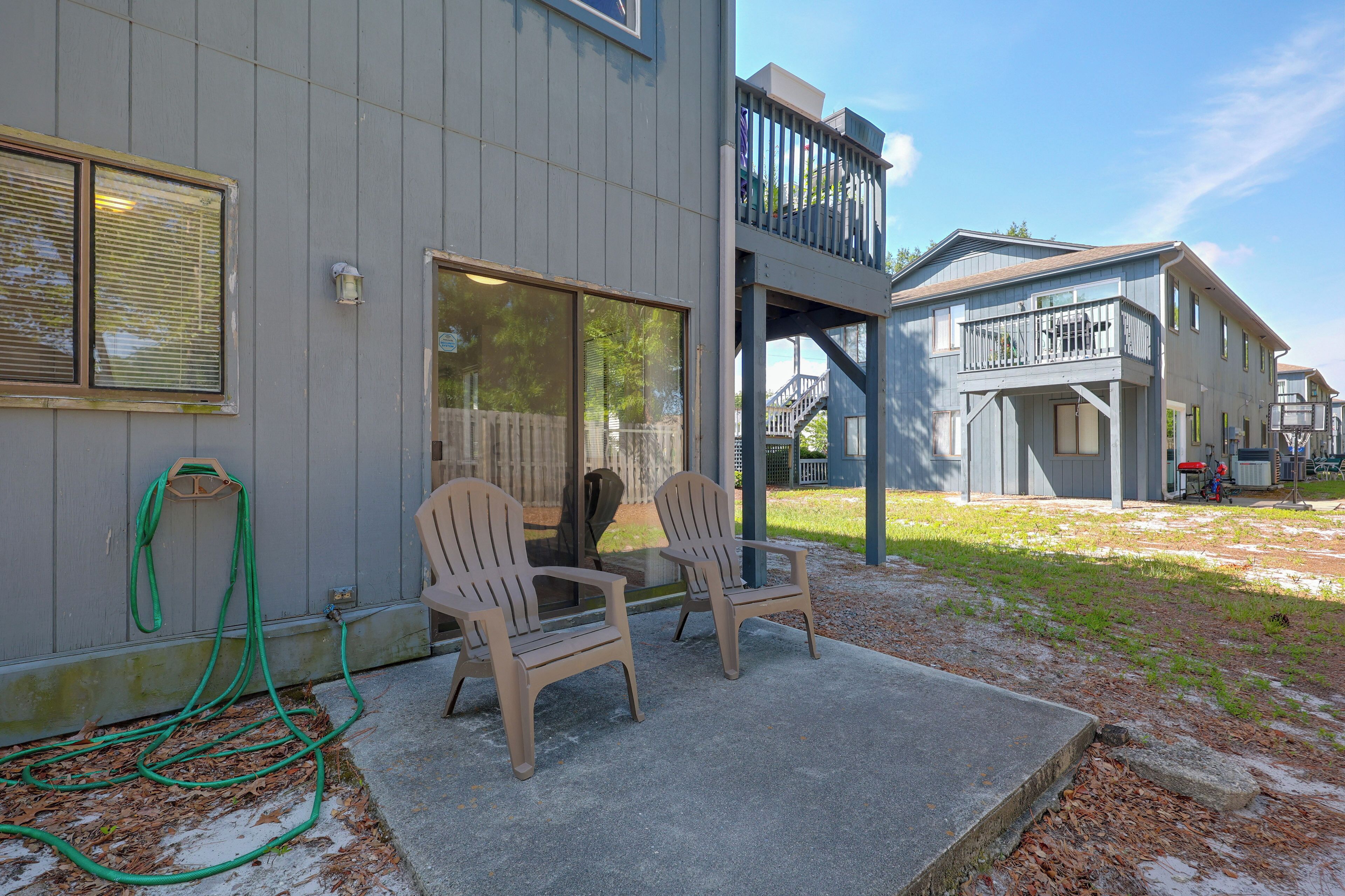 A residential building with a covered porch, two chairs, and a hose.