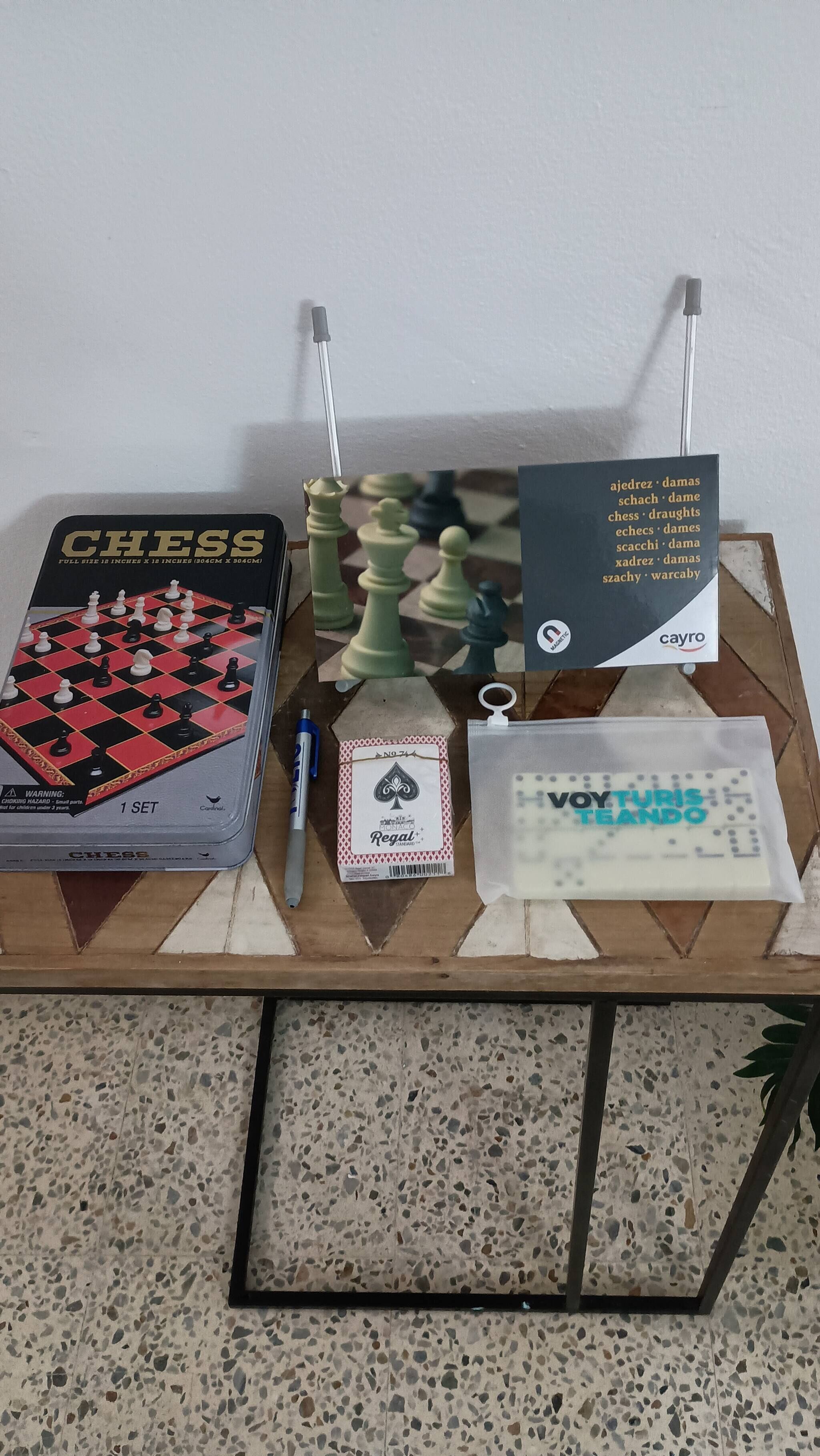 Ein Schachspiel auf einem Tisch, bestehend aus Schachbrett, Stift, Karte und einem Schild.