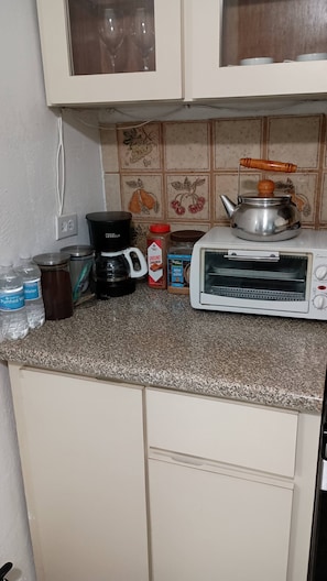 Eine Küche mit einem Toaster, einer Kaffeemaschine, einem Glas gemahlenem Zimt und einer Wasserflasche.