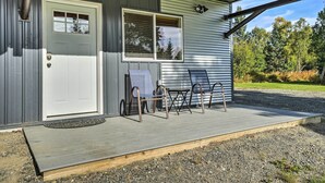 A building with a white door, a window, and a porch with two chairs and a table. - Steps to Fritz Creek! 2-Unit Family Retreat (Fritz Creek)