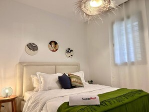 Ein Schlafzimmer mit Bett, Kopfstütze, Wandlampe und drei Wandbildern.
