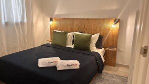 Ein Hotelzimmer mit Bett, Kissen, Nachttisch und einer Wandleuchte.
