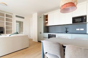 Eine moderne Küche mit integrierten Geräten, ein Essbereich mit Tisch und Stühlen sowie ein begehbarer Kleiderschrank mit Regalen.