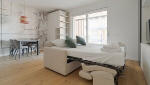 Quarto moderno com cama de solteiro que se transforma em cama de casal, escrivaninha e área de refeições.