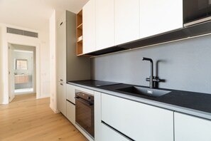 Eine moderne Küche mit weißen Schränken, einer schwarzen Arbeitsplatte und einem eingebauten Backofen.