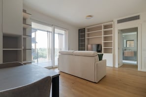 Ein modernes Wohnzimmer mit einer Couch, einem Esstisch und integrierten Regalen.