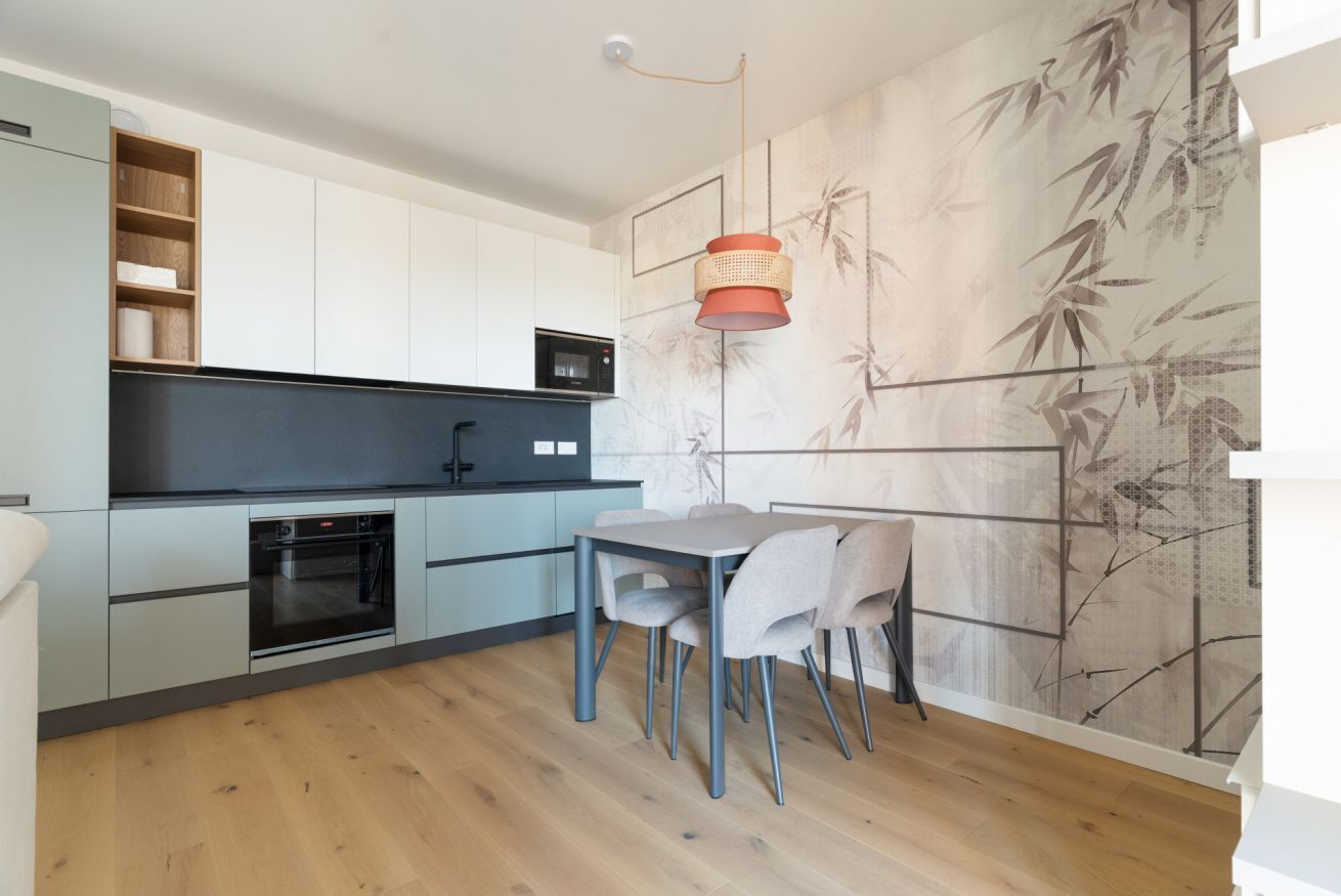 A modern kitchen with a dining area, featuring a microwave, oven, and a table with chairs.