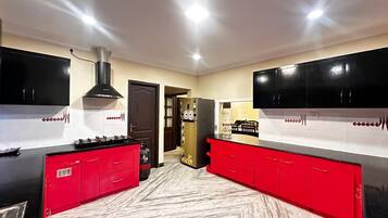 A kitchen with red cabinets, a black stove, and a refrigerator with a cartoon character.