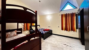 Ein Schlafzimmer mit Etagenbett, einem Einzelbett, einem Kleiderschrank, einer Deckenleuchte und einem Fenster mit Vorhängen.