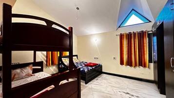 A bedroom with a bunk bed, a single bed, a wardrobe, a ceiling light, and a window with curtains.