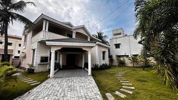 A two-story house with a paved driveway leading to a covered entrance.
