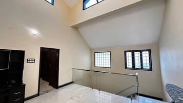 A spacious room with a high ceiling, a glass railing, and a television on a stand.