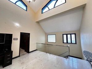 A spacious room with a high ceiling, a glass railing, and a television on a stand. - Spacious 5-bedroom bungalow in gorgeous Chennai with AC (Chennai)