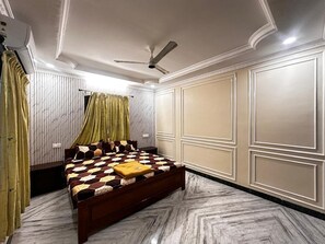 Een slaapkamer met een bed, een plafondventilator en een raam met gordijnen.