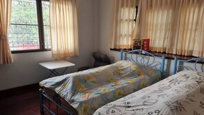 Un dormitorio con dos camas, una mesita y una ventana con cortinas.