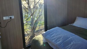 A bedroom with a bed, a window, and a view of trees. - Orchard Wanderer by Tiny Away (Darraweit Guim)